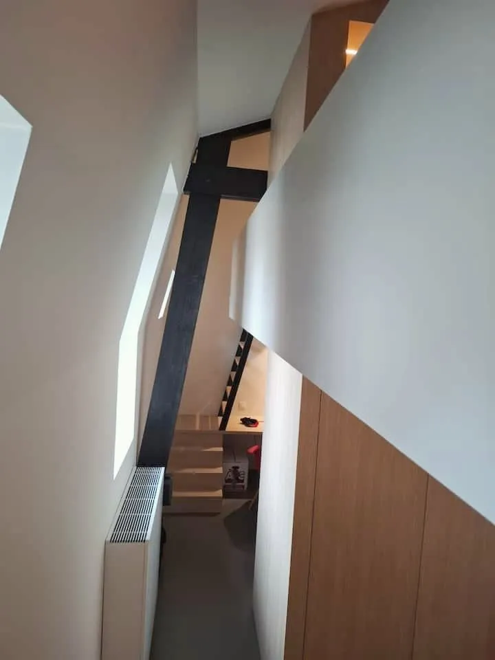 Steep stair and black beam up to a sleeping mezzanine