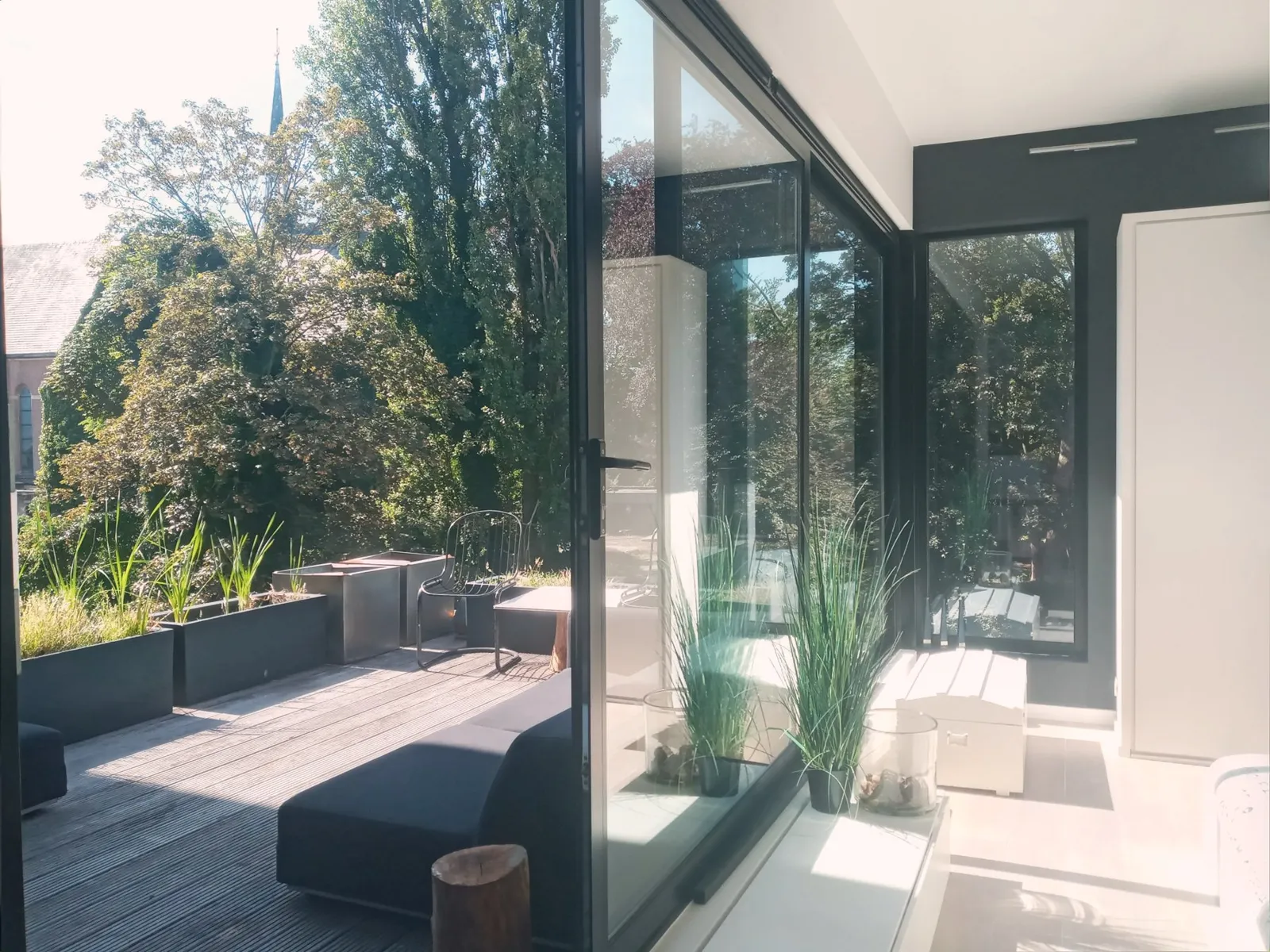 Bedroom terrace with lounge seats and the church tower beyond the trees